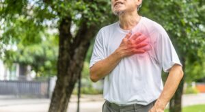 An elderly man clutches his chest in pain, showing symptoms of heart failure and highlighting the importance of cardiovascular disease awareness and heart health care.
