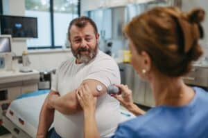 Doctor applying continuous glucose monitor sensor on patient’s arm to track blood sugar and manage type 2 diabetes risk