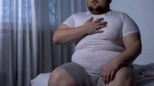 Man grasping his chest in discomfort, concept of high blood pressure symptoms and cardiovascular health concerns.