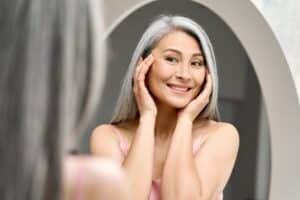 A woman looking in the mirror considering hair and skin changes during menopause