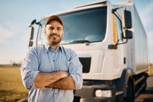 Truck Driver standing in front of his truck and smiling